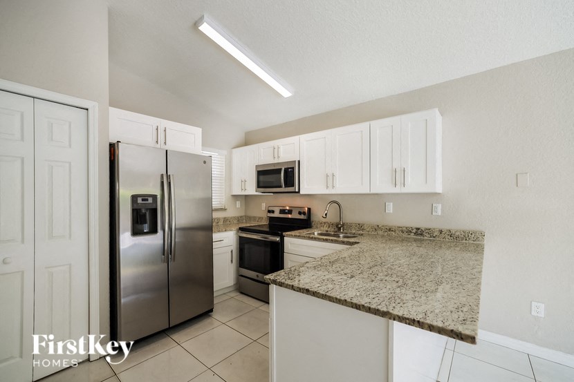a kitchen with granite counter tops and a stainless steel refrigerator