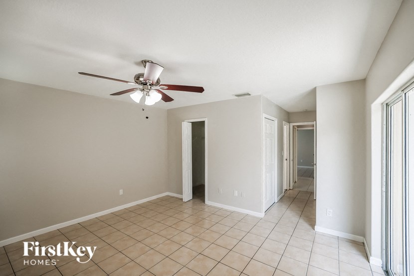 a empty living room with a ceiling fan and a tiled floor