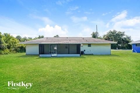 A house with a white exterior and a yellow roof is surrounded by a grassy lawn.