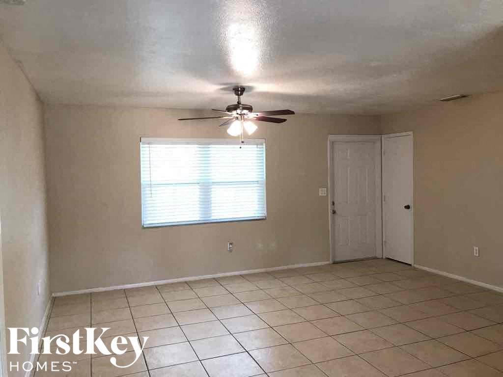 A room with a ceiling fan and a window with blinds.