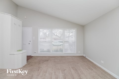 a spacious living room with a large window and white cabinets