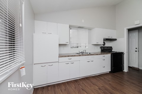 a kitchen with white cabinets and a sink and a window