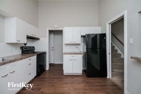 a kitchen with white cabinets and a black refrigerator