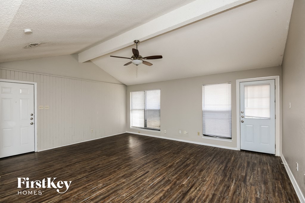 A spacious room with wooden floors and a ceiling fan.