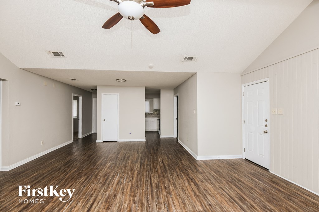 A spacious room with wooden floors and a ceiling fan.