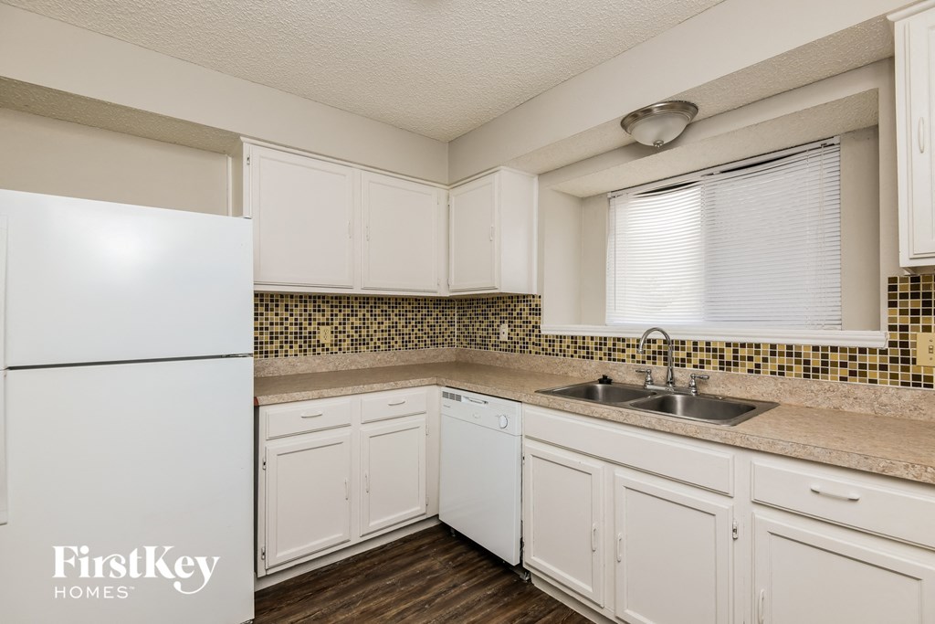 A kitchen with white cabinets and a white fridge.