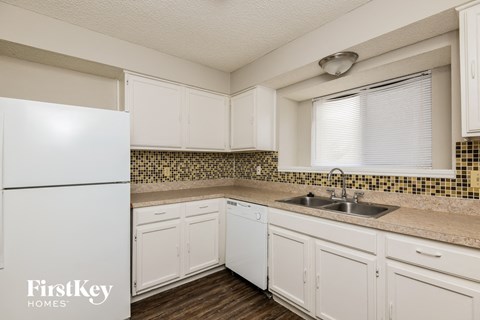 A kitchen with white cabinets and a white fridge.