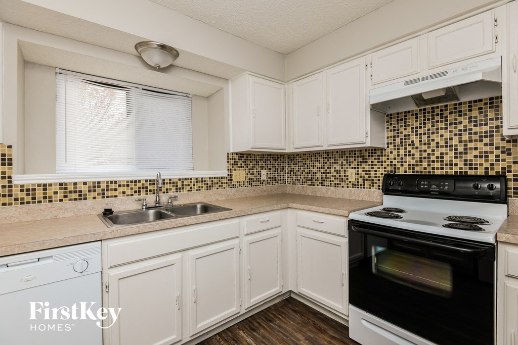 A kitchen with white cabinets and a black stove top oven.