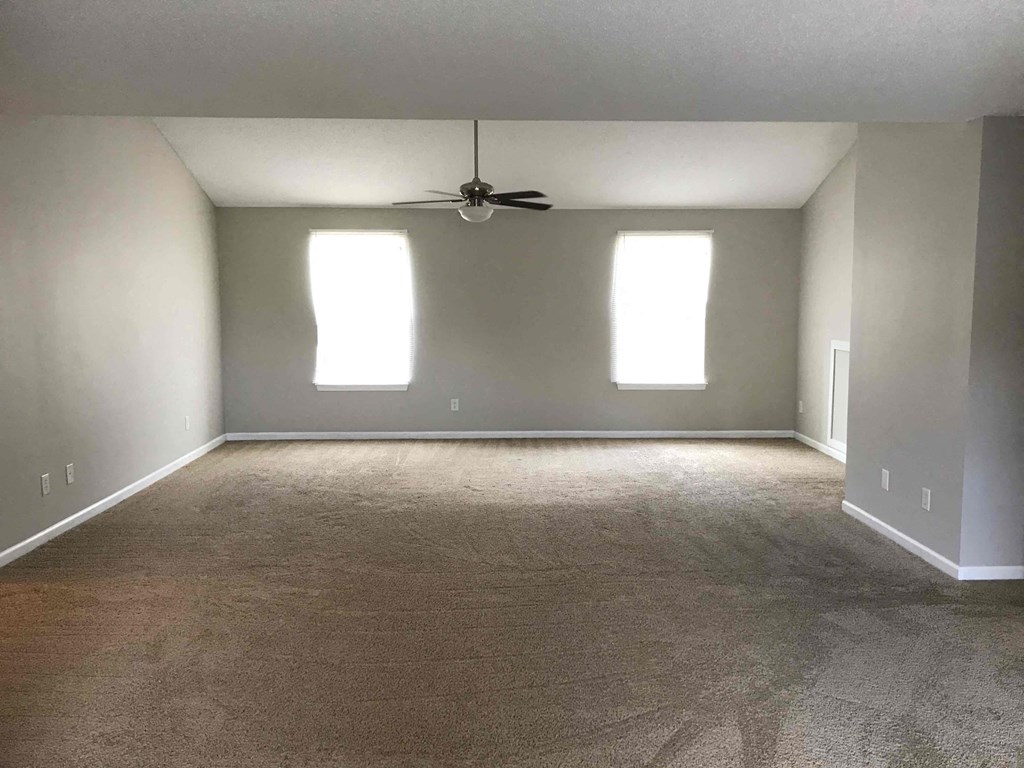 an empty living room with a ceiling fan