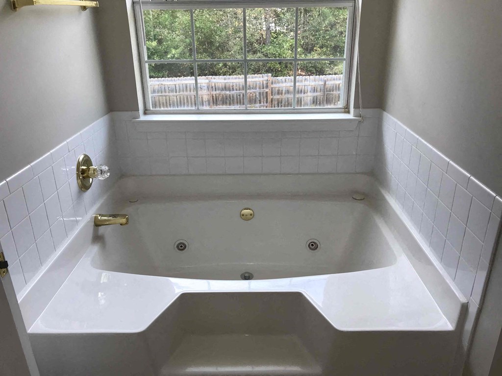 a white bath tub in a bathroom with a window