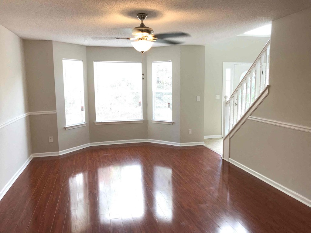 an empty living room with wood floors and a ceiling fan