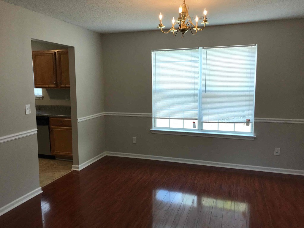 an empty living room with hard wood floors and a window