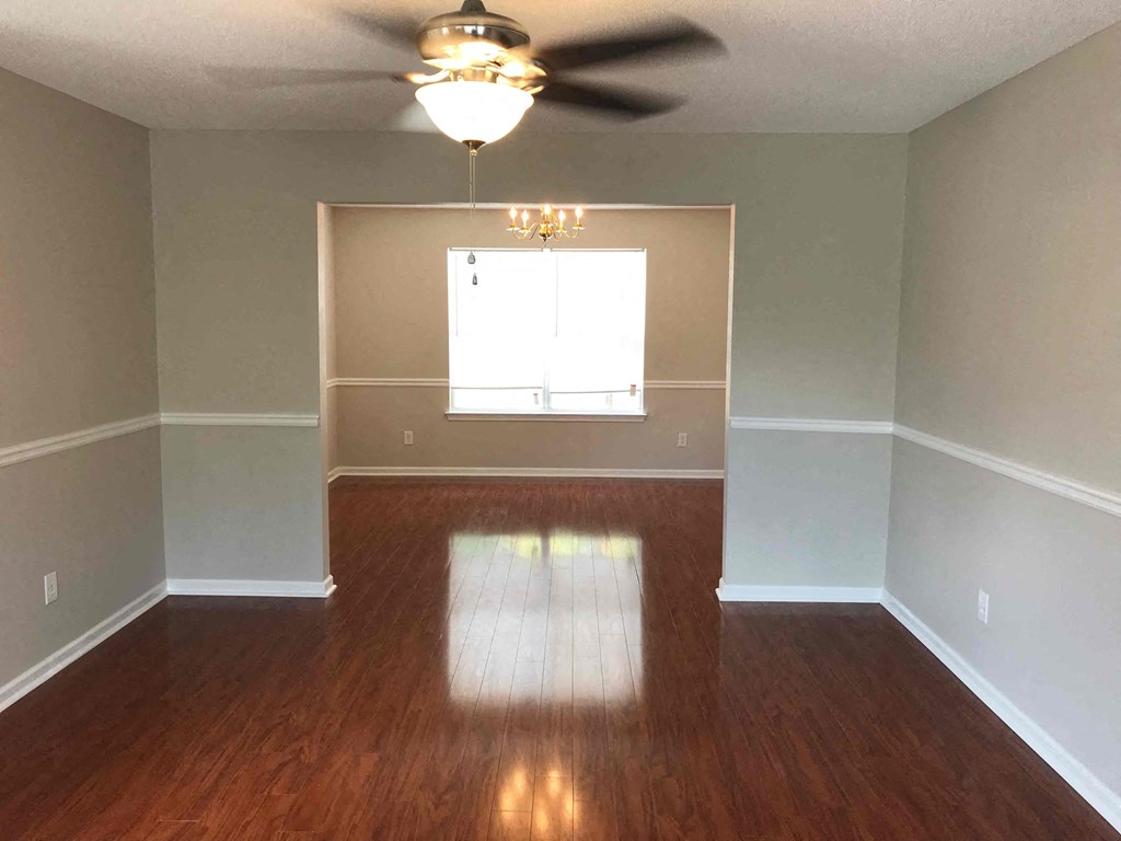 an empty living room with wood floors and a ceiling fan