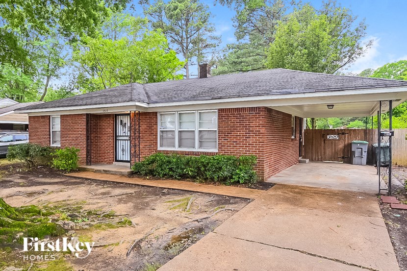 a small brick house with a porch and a driveway