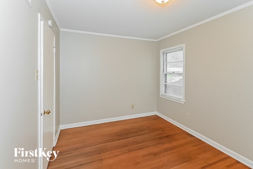 an empty bedroom with wood floors and a window