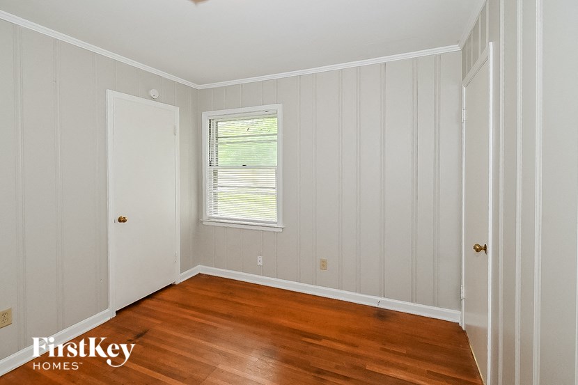 a room with wooden floors and a window and white walls