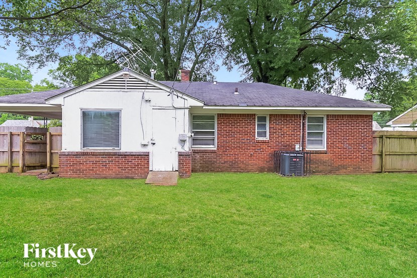 a small brick house with a yard and a fence