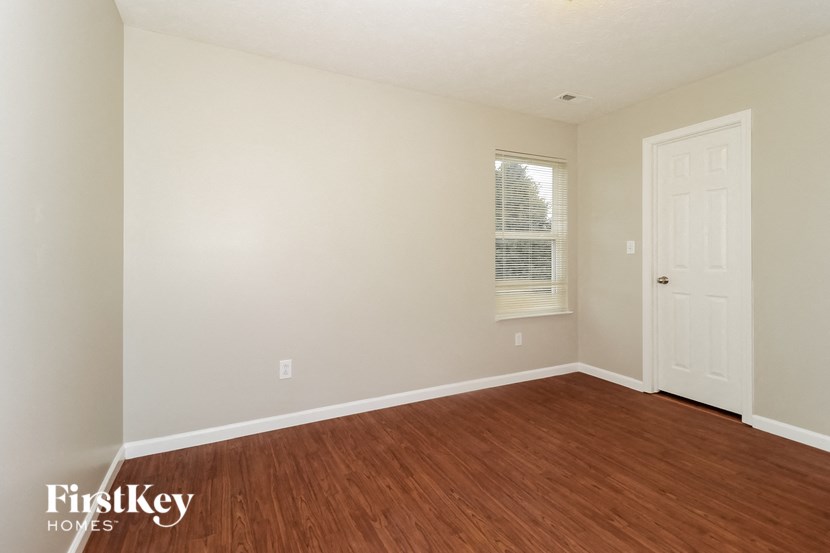 a bedroom with wood flooring and a white door
