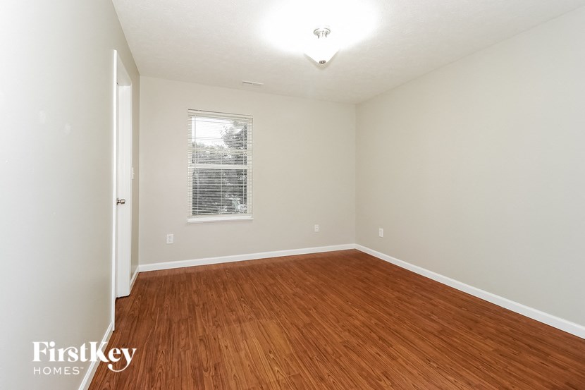 a bedroom with wood flooring and a window
