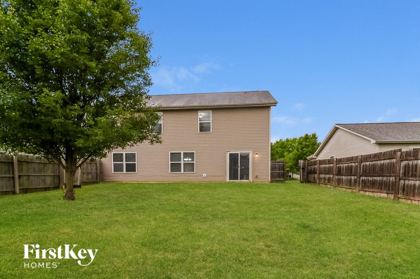 the back of a house with a yard and a fence