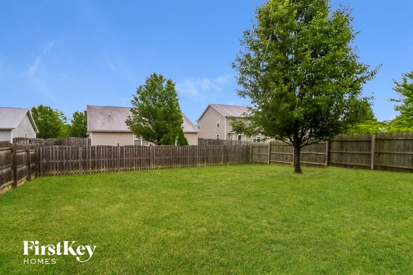 the backyard of a house with a fence and a tree