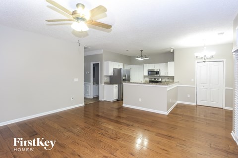 A spacious kitchen and living room with wooden floors and white walls.