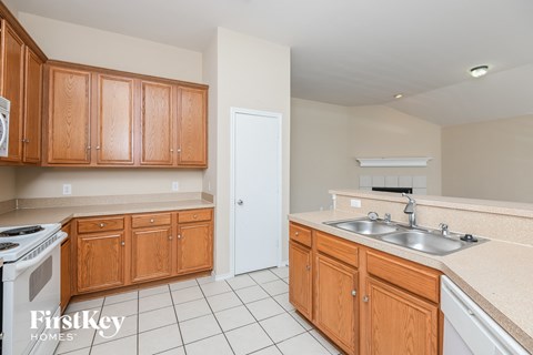 A kitchen with wooden cabinets and a white stove top oven.