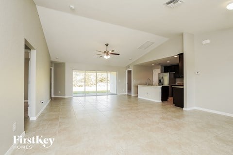 an empty living room and kitchen with a ceiling fan