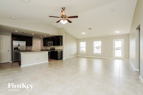 an empty kitchen and living room with a ceiling fan