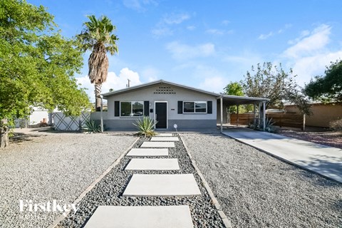 A house with a gravel driveway and a palm tree in the background.