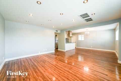 A spacious room with wooden floors and a white ceiling with lights.