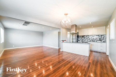 A spacious kitchen and living room with wooden floors and white walls.