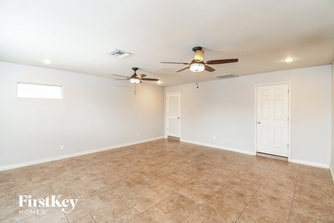 A spacious room with a ceiling fan and tiled floor.