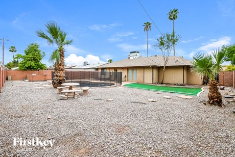 A house with a gravel yard and palm trees.