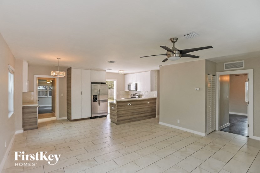 A spacious kitchen and living room with a ceiling fan and lighting.