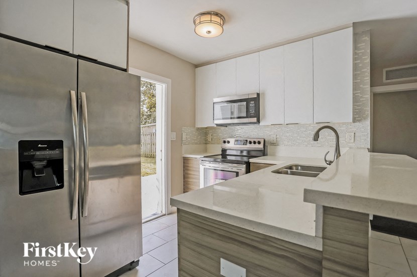 A modern kitchen with a stainless steel refrigerator and a microwave above the stove.