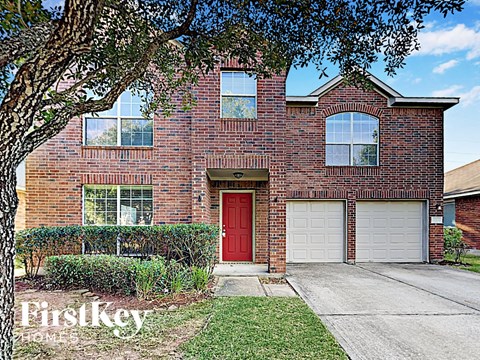 a red brick house with a red door and white garage doors