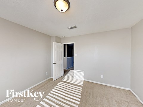 a spacious living room with carpeted flooring and a white door to a hallway