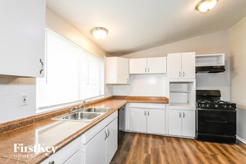 A kitchen with white cabinets and a wooden counter top.