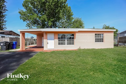 a small tan house with a lawn and a driveway