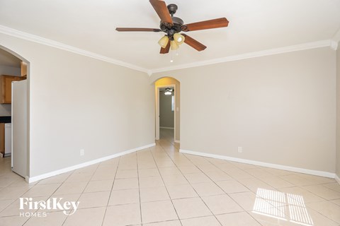 an empty living room with a ceiling fan and tiled floors