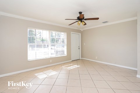 an empty living room with a ceiling fan and a window