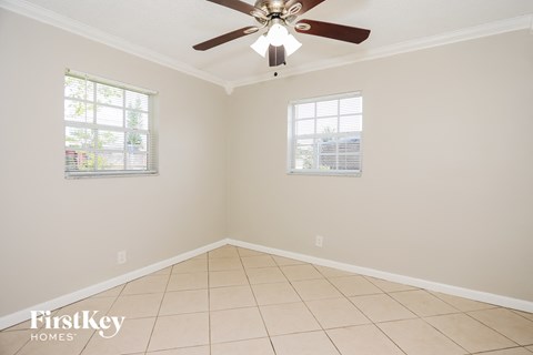 an empty room with a ceiling fan and two windows