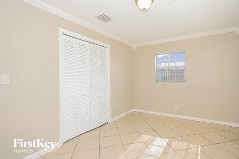 an empty living room with a door to a closet and a tiled floor