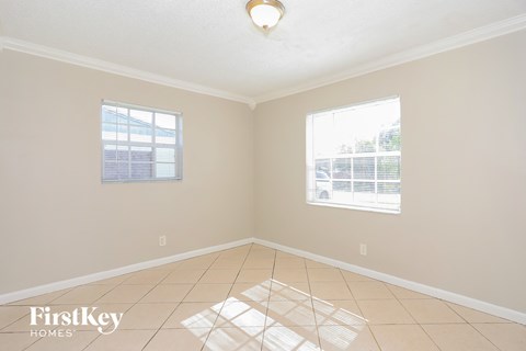 an empty living room with two windows and a tiled floor