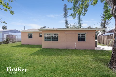 a small pink house with a yard and a tree