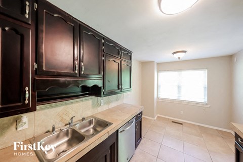 a kitchen with dark wood cabinets and a stainless steel sink