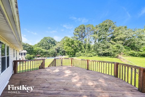 a deck overlooking a yard with trees and a blue sky