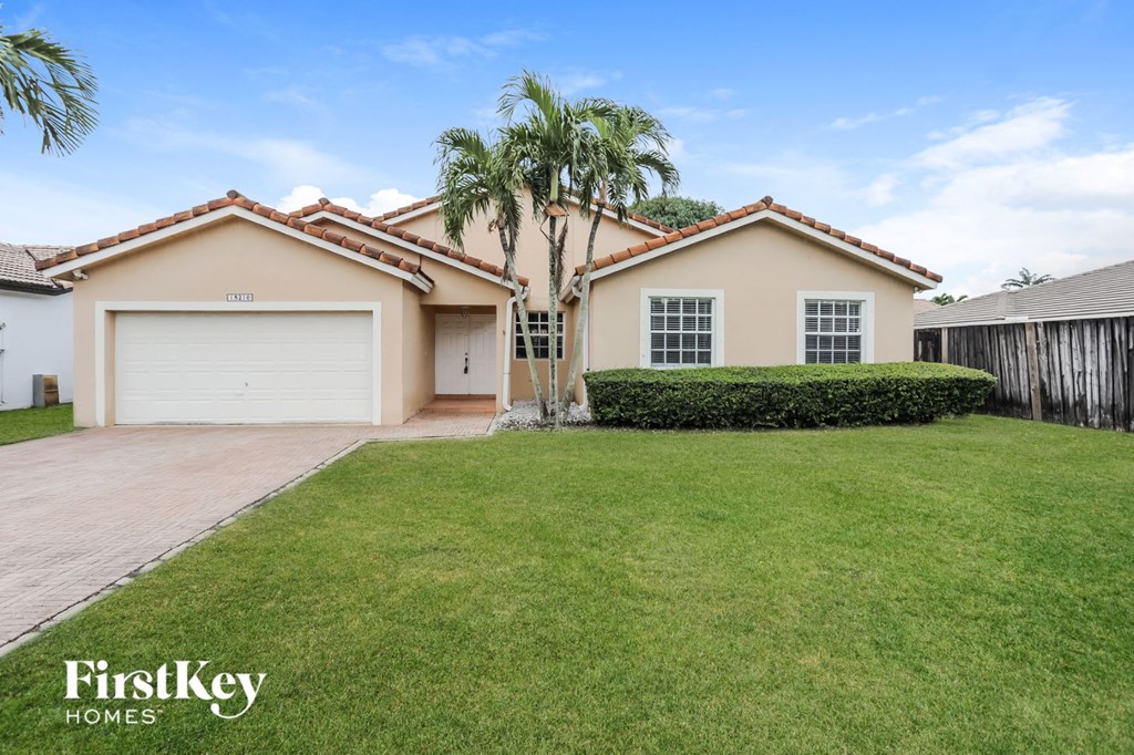 a home with a lawn and palm tree in front of it