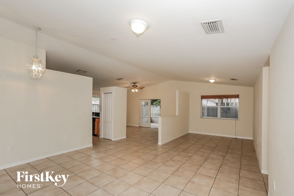 a spacious living room with tile flooring and white walls